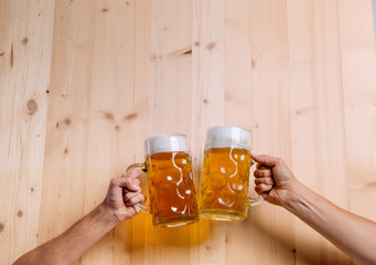 Two unrecognizable men clinking with beer mugs, studio shot