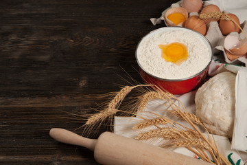 ingredients for homemade bread on vintage wooden background and towel with embroidered ears of wheat, milk, eggs, flour, dough, bread