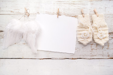 New Born or baptism Greeting Card. Blank with baby girl gloves ans angel wings on white wooden...