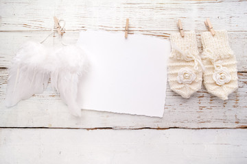 New Born or baptism Greeting Card. Blank with baby girl gloves ans angel wings on white wooden background