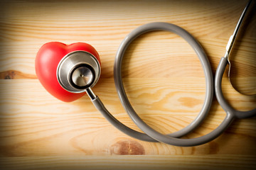 Stethoscope with red heart on a wood background