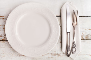 Plate, fork and knife on white wooden table