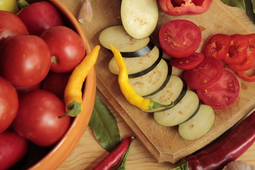 Tomatoes and eggplant cut on a wooden board.