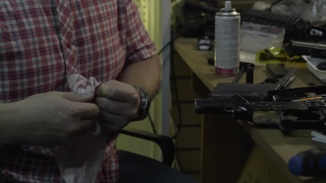 Man repairing weapons. The guy with the beard cleans and repairs armekie rifles and pistols at his desk in the studio