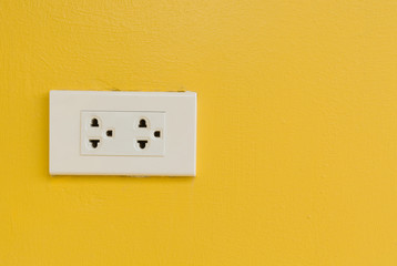 White electric plug on yellow wall.