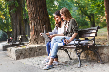 Portrait of two businesswomen sitting in park using laptop. Business team working online togetherness while consulting.
