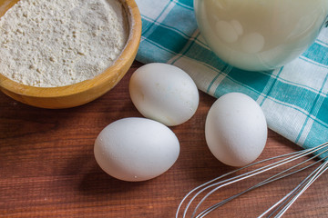 Fototapeta na wymiar Eggs, flour and milk on wooden background
