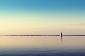 Plakaty  Water landscape with white sailing boat on calm waters in the light of the sunset. Toned and processing photos.