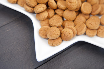 Traditional Dutch candy pepernoot on white plate on white wooden background