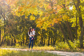 Fototapeta premium Young mother and her toddler girl have fun in autumn