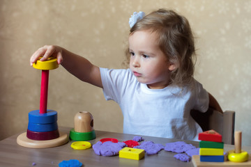 little girl playing with bright toys at the table