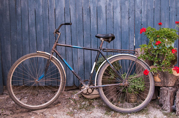 Fototapeta na wymiar Old bicycle near a blue wooden fence in village