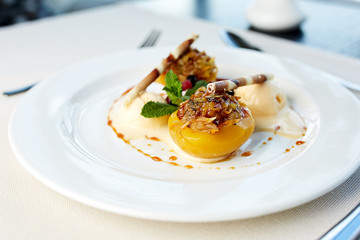 Peach with nut filling and vanilla ice cream  on a table