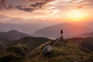 Man standing on a mountain summit at sunset