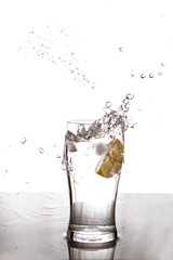 Lemon dropping on a glass and splashing water