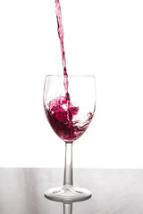 Glass filling with red wine with a seamless white background