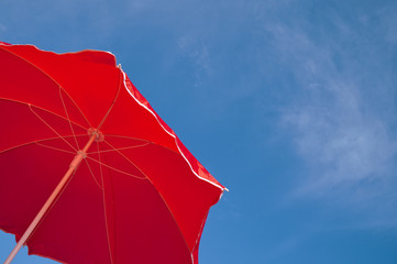 Red beach umbrella and blue sky. Summer beach vacations