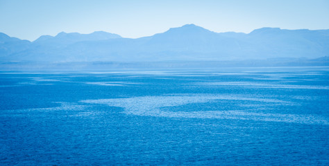 View of ocean streams from a cruise ship with blue skies and mountains in the distance. - 121289674