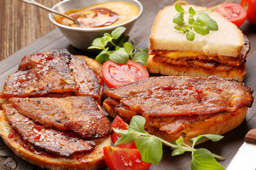 Sandwich with fried bacon on wooden background