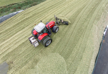 Luftbild, roter Trecker beim Planieren eines Maissilagehaufens