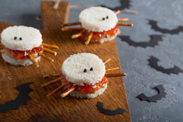 Spooky peanut butter and jelly spider sandwiches with paper bats for halloween on a cutting board