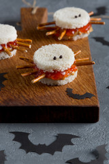 Spooky peanut butter and jelly spider sandwiches with paper bats for halloween on a cutting board