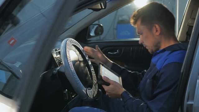 Professional car mechanic working in modern auto repair service and checking engine