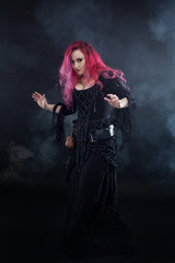 Fototapeta na wymiar Witch creates magic. Attractive woman with red hair in witches costume