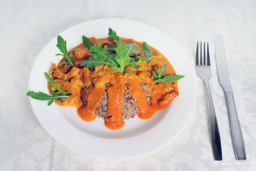Beef stroganoff with boiled buckwheat served on a white plate with an arugula