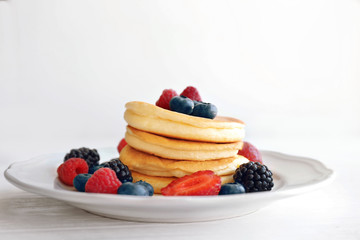 Plate with delicious pancakes and berries on table, closeup