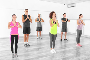 Fototapeta premium Group of people doing yoga exercises in gym
