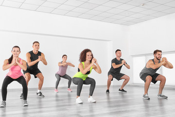 Fototapeta na wymiar Group of people doing yoga exercises in gym