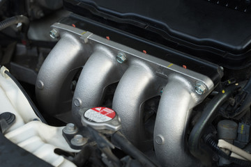 Silver colored car engine with four cylinders