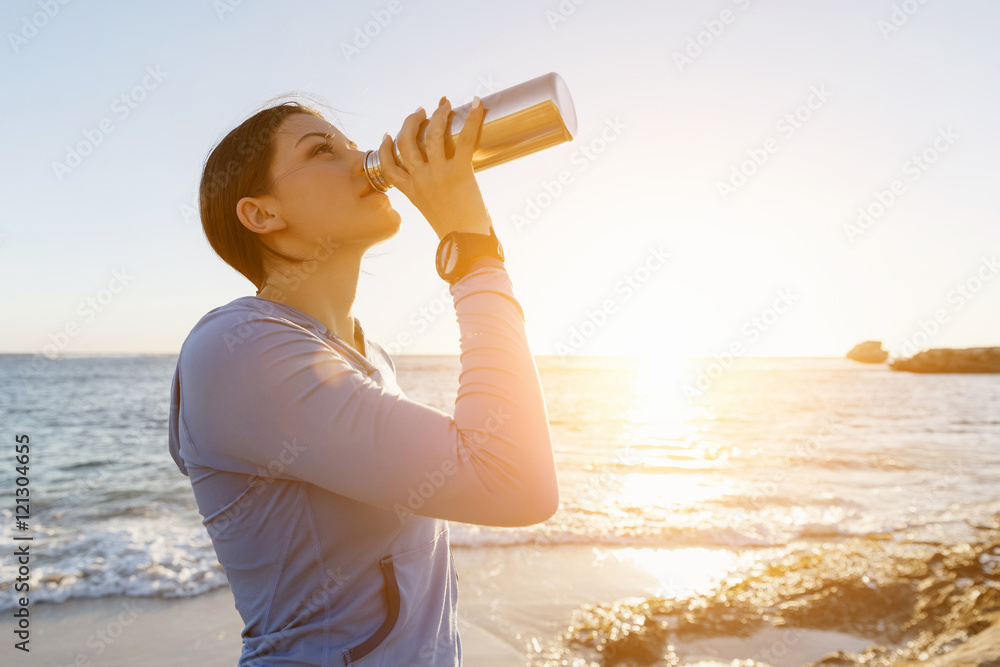 Wall mural woman drinking water on beach