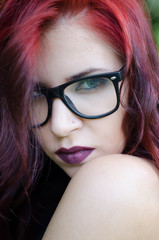 Fototapeta na wymiar Portrait of beautiful fashionable girl with long red hair, eyeglasses and nose piercing