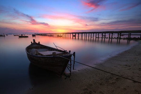Small fishing boats moored beached on the beach during time the sunset and the beautiful natural of the colorful sky at Bang Phra beach , Chonburi province in Thailand