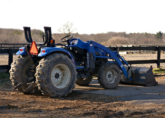 A blue farm tractor is ready for work with the fields in the background
