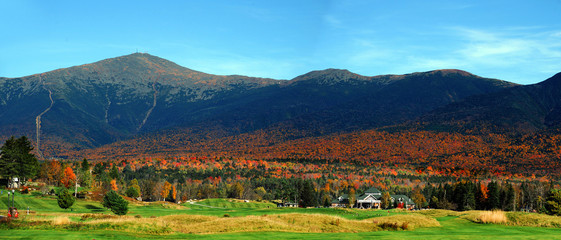 autumn mountain, colorful forest and green golf course at the foot of mountain