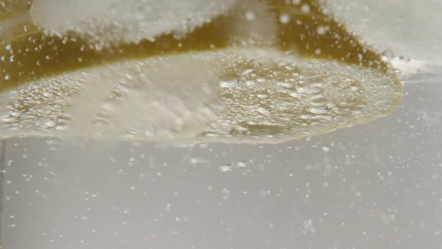 Highly carbonated water and ice cubes in the glass close-up 4K 2160p 30fps UltraHD footage - Lemon slice in cooled tonic 3840X2160 UHD video