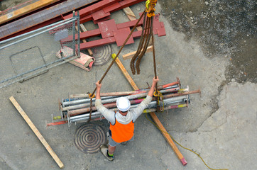 Builder manages the construction process of crane hook lifting w - obrazy, fototapety, plakaty