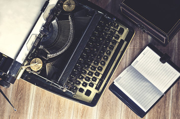 Vintage typewriter on the old wooden desk with black board space for your text.