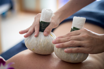 woman getting thai herbal compress massage in spa
 - obrazy, fototapety, plakaty