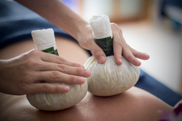 woman getting thai herbal compress massage in spa
