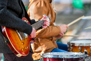 Fototapeta premium Muzyczni wykonawcy uliczni na zewnątrz jesienią. Środkowa część korpusu z gitarą.