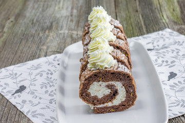 Chocolate roulade filled with whipped cream on white tray
