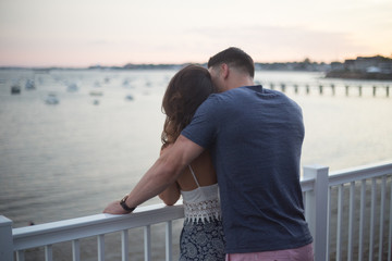 Man Embracing Girlfriend on Deck Overlooking Water