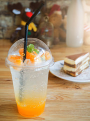 Tiramisu cake and Glass of orange soda on wooden table in coffee shop