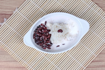 Black bean and sticky rice in sweet coconut cream topped coconut milk on bamboo. Top view.