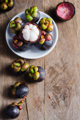 Mangosteen and cross section showing the thick purple skin and w