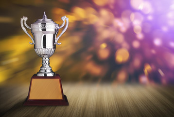 silver trophies on wood table with abstract bokeh lights. defocu